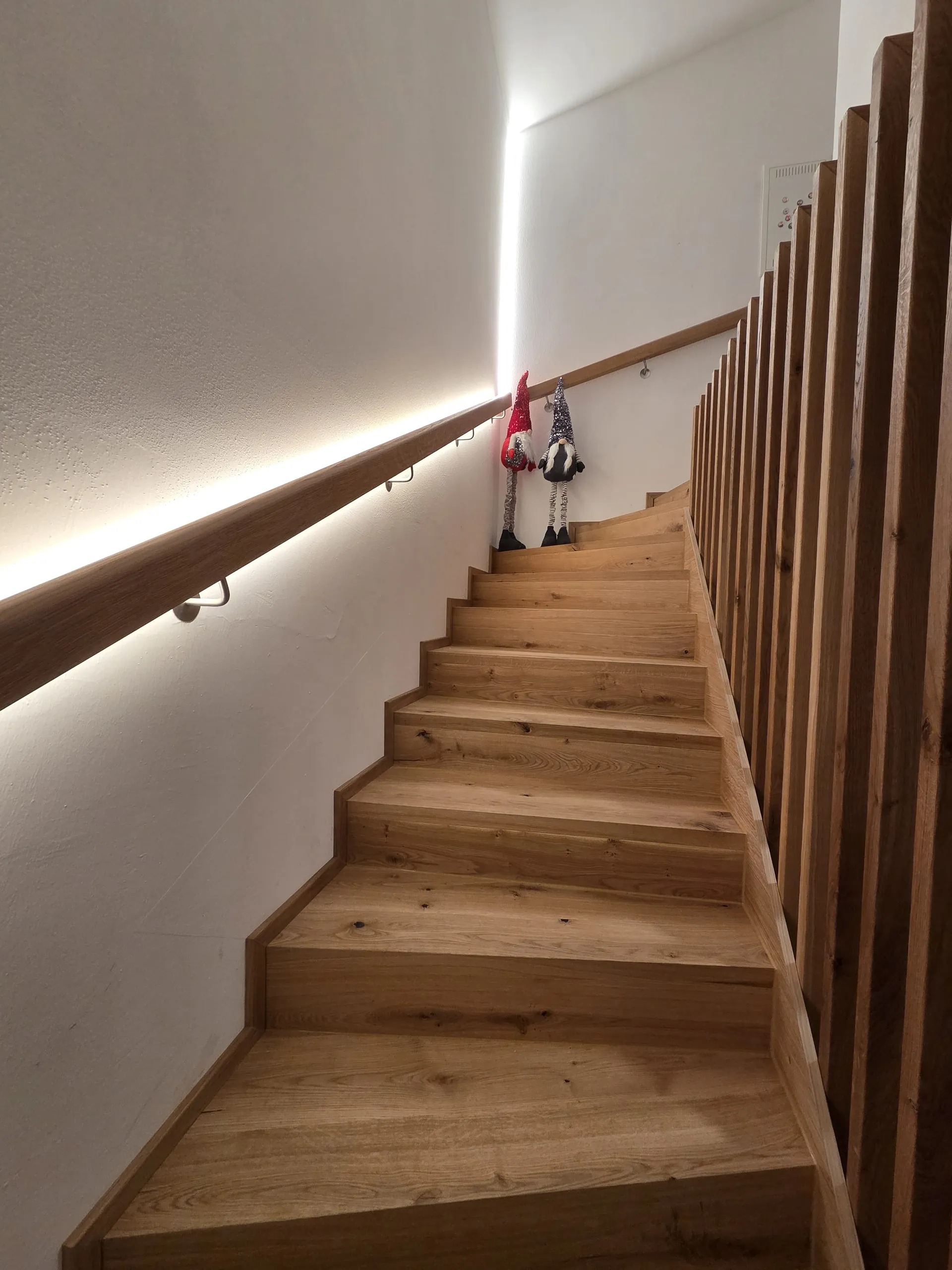 Blick die beleuchtete Eichenstiege hinauf ins Dachgeschoss