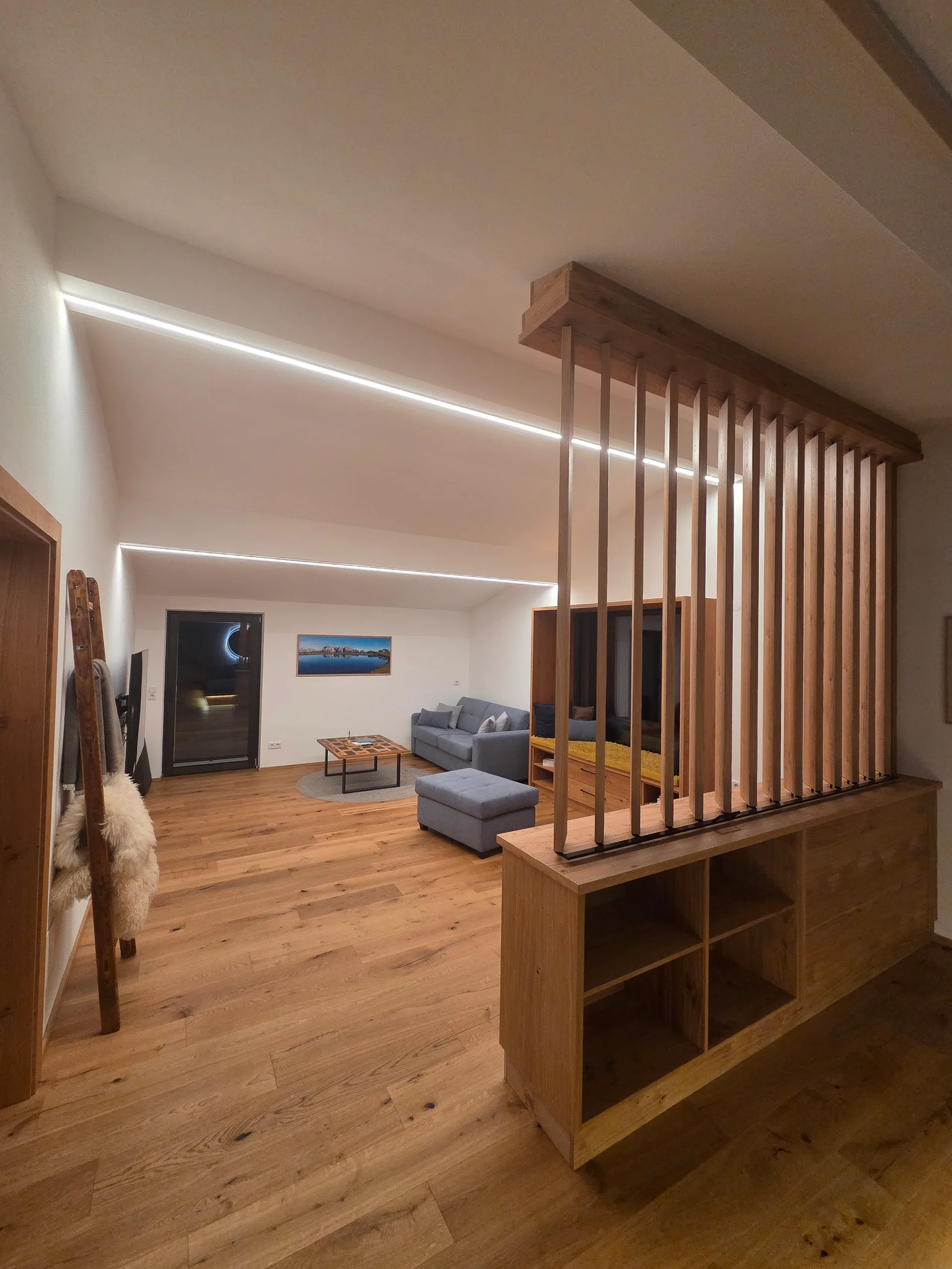 Blick vom Lamellen-Raumteiler in den Wohnbereich mit Couch und Fernseher